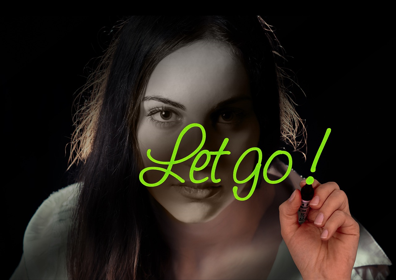 Woman writing Let Go on a window in lime green marker